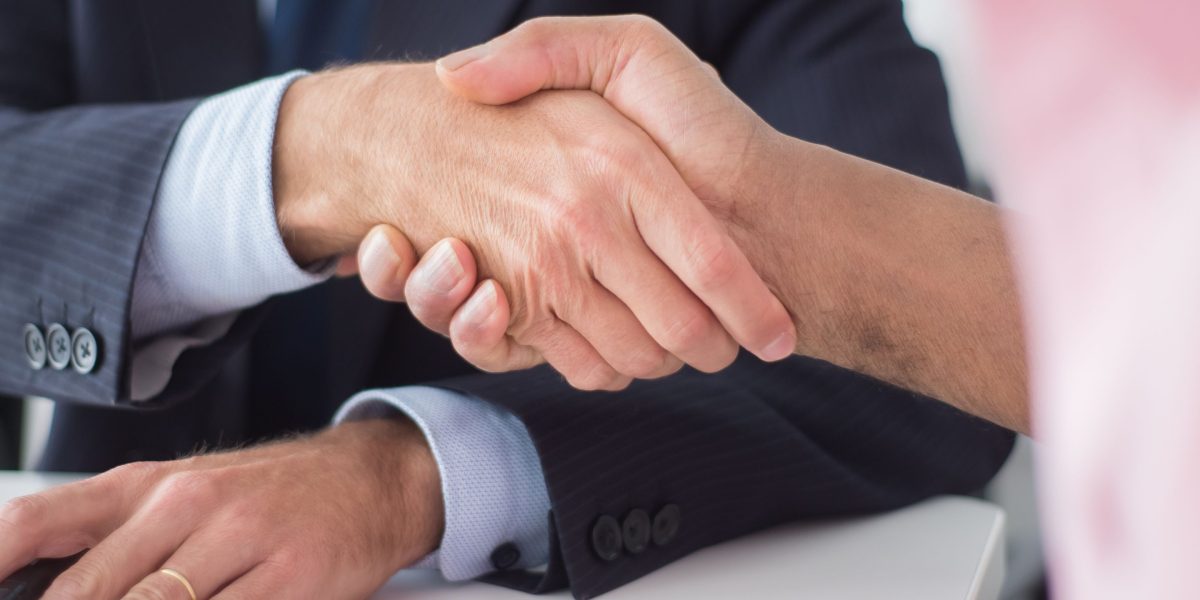 Two professionals shaking hands, symbolizing a commitment to a robust framework for reliable AI design and brand protection.