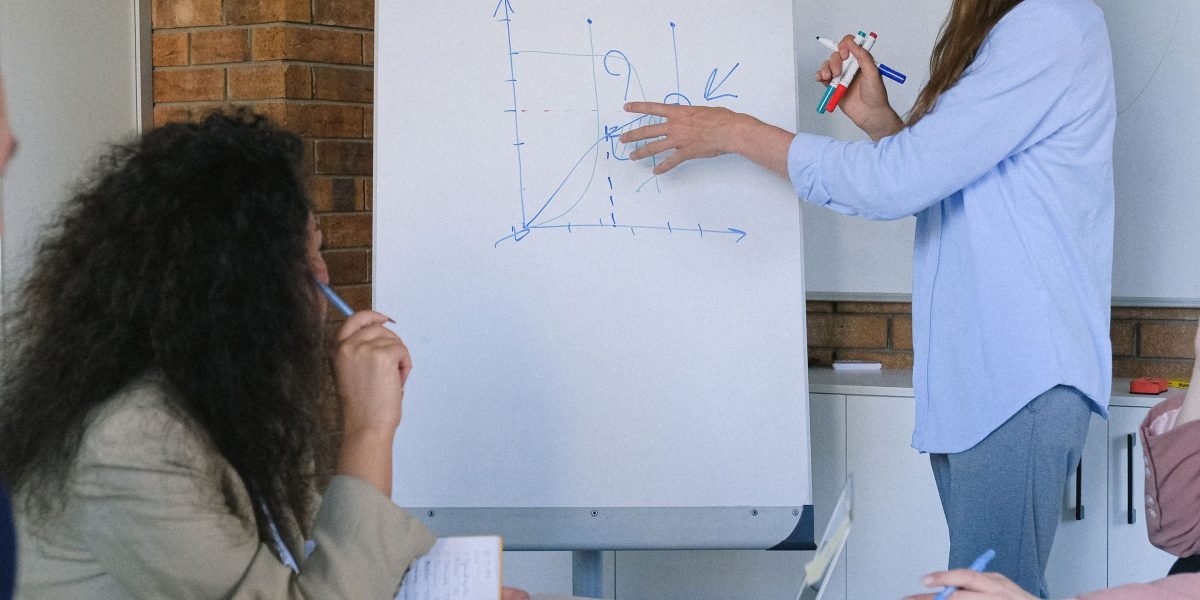 A diverse group of colleagues working together, brainstorming solutions to a complex project on a whiteboard.