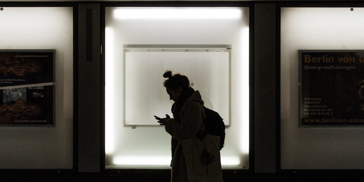 A commuter looking confused while trying to navigate public transport using a phone.