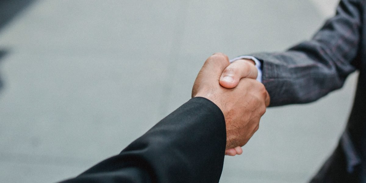 Two professionals confidently shaking hands, representing successful collaboration and the establishment of trustworthy AI systems.